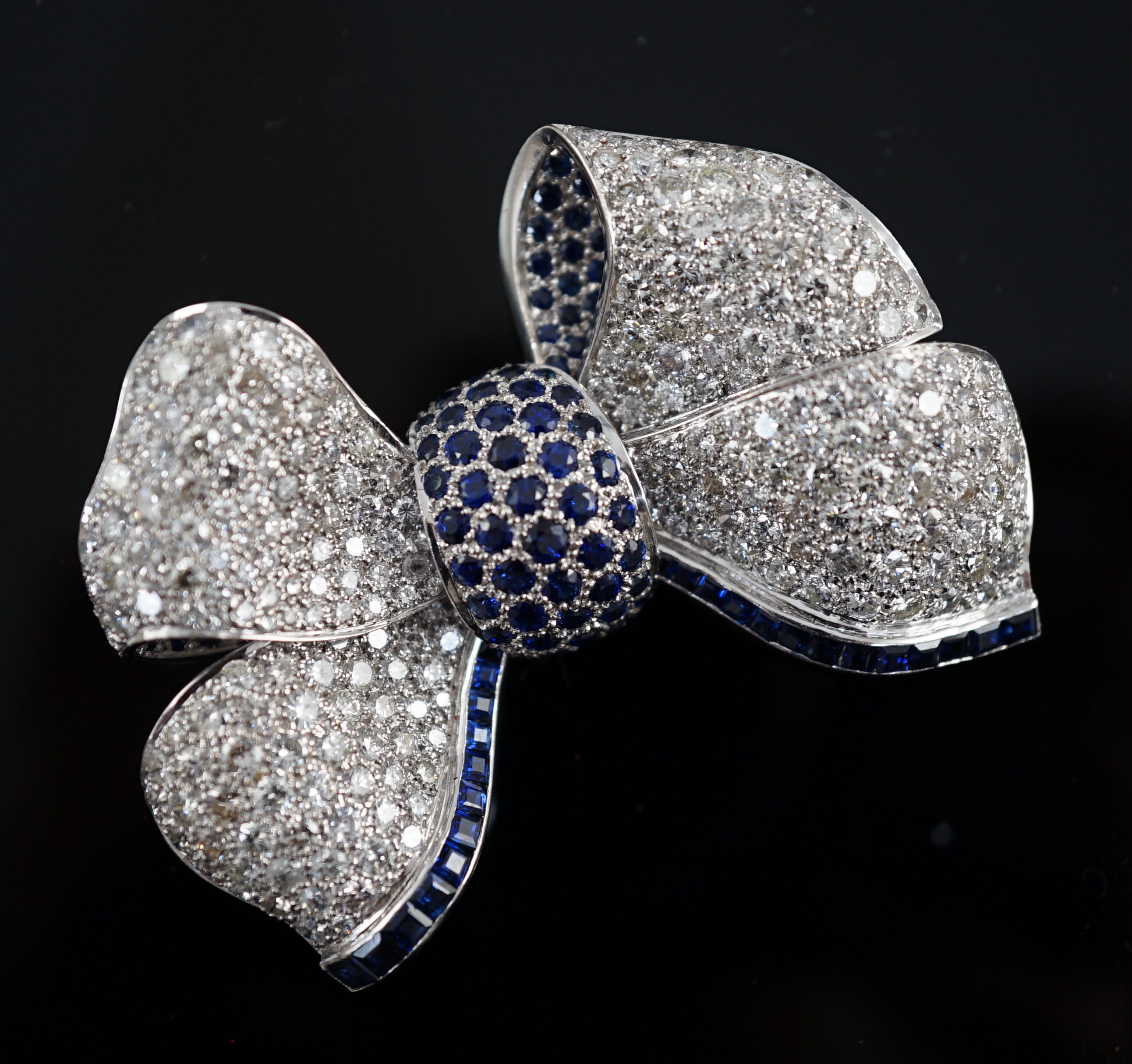 A modern white gold and pave set diamond and sapphire set ribbon bow brooch